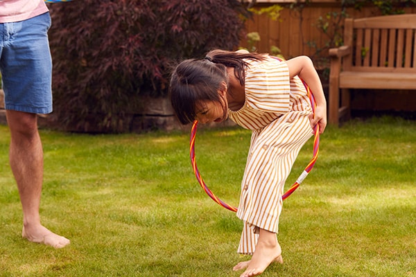 Ein Mädchen hat viel Spaß mit ihrem Hula Hoop im Garten